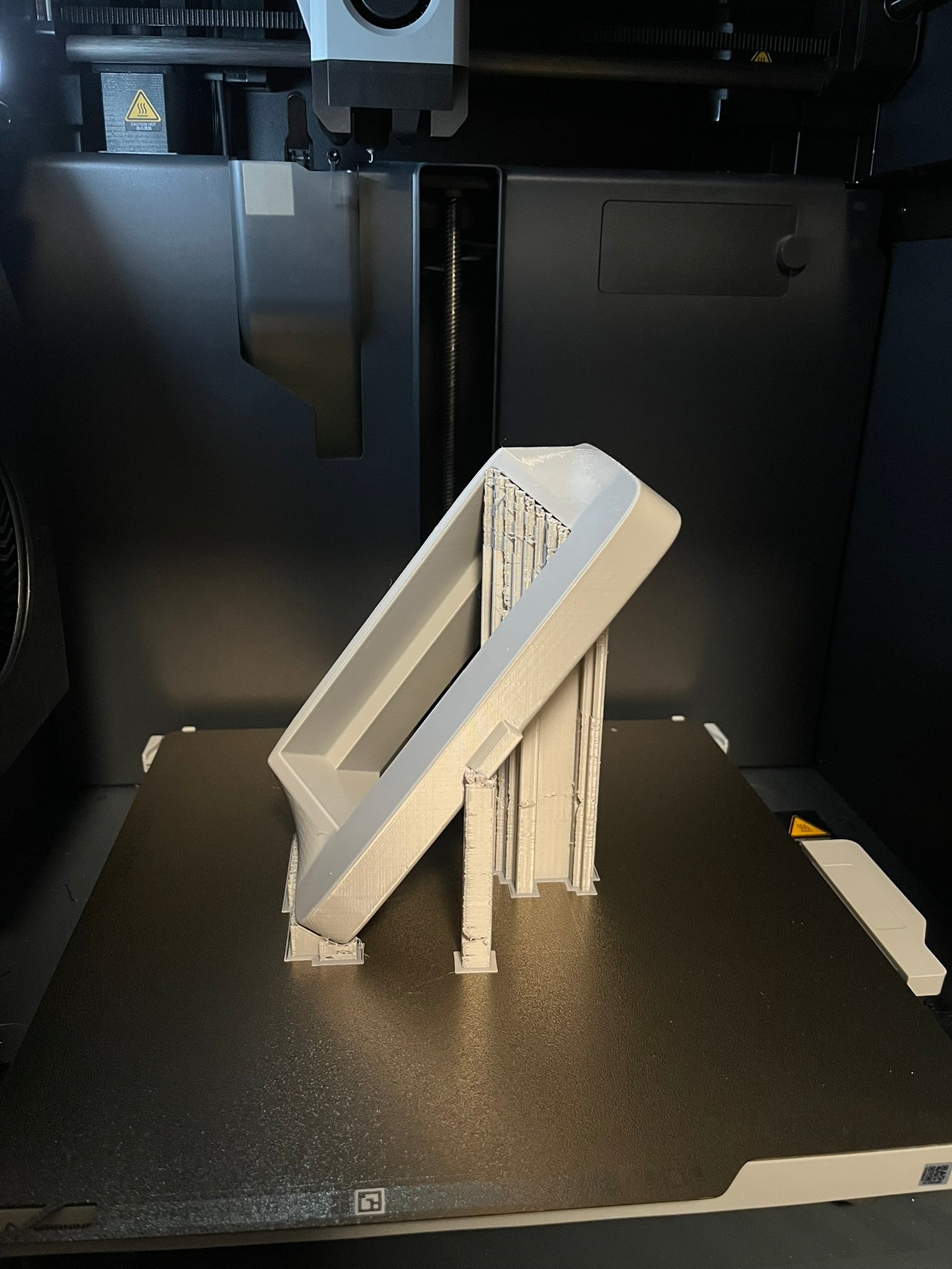 3D printed object on a black surface with a 3D printer in the background