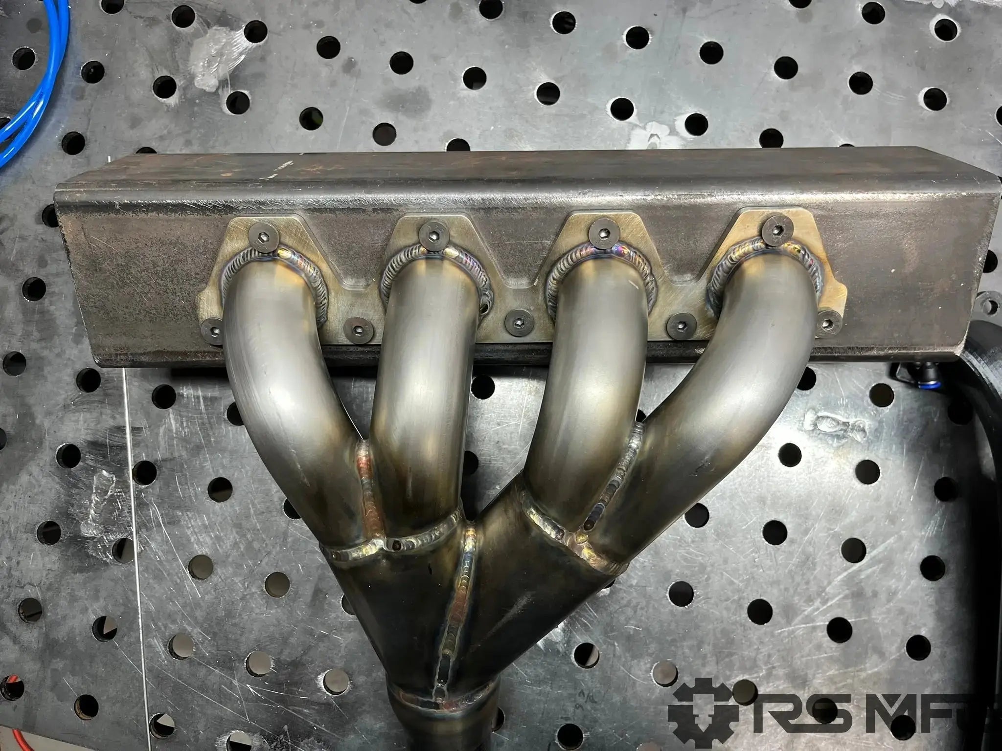 Metal exhaust manifold on a perforated metal surface